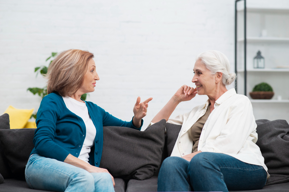 две взрослые женщины сидят на диване и беседуют